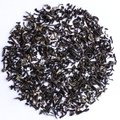 Loose-leaf tea leaves, dark brown to black with subtle green and light brown highlights, arranged in a circular pile on a plain white background.