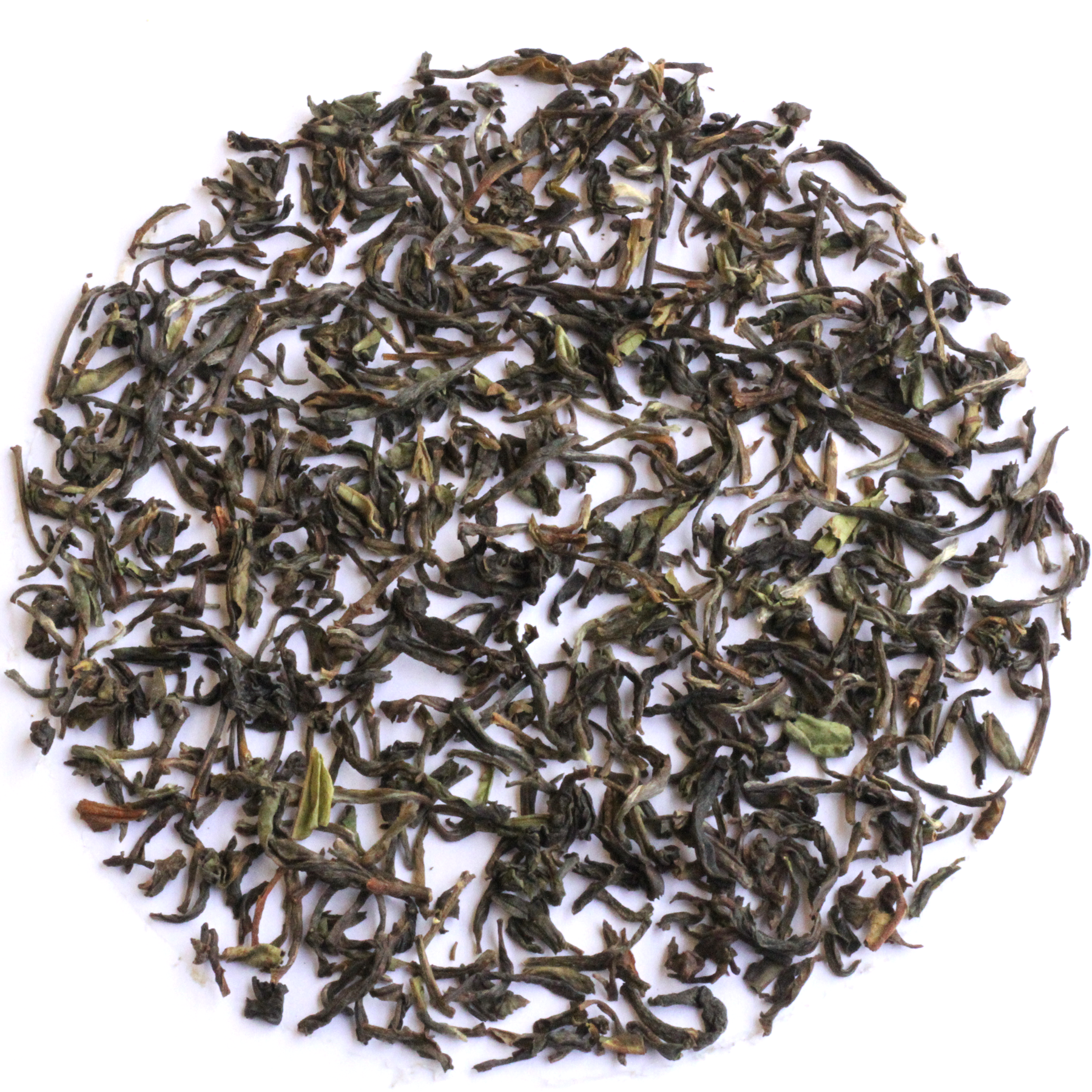 Loose-leaf tea leaves, primarily dark green with some brown and light green accents, arranged in a circular pile on a solid white background.