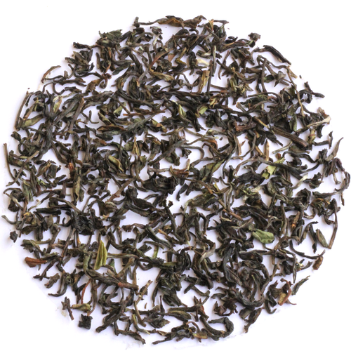 Loose-leaf tea leaves, primarily dark green with some brown and light green accents, arranged in a circular pile on a solid white background.
