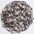 Loose-leaf tea leaves arranged in a circular pile on a plain white background.