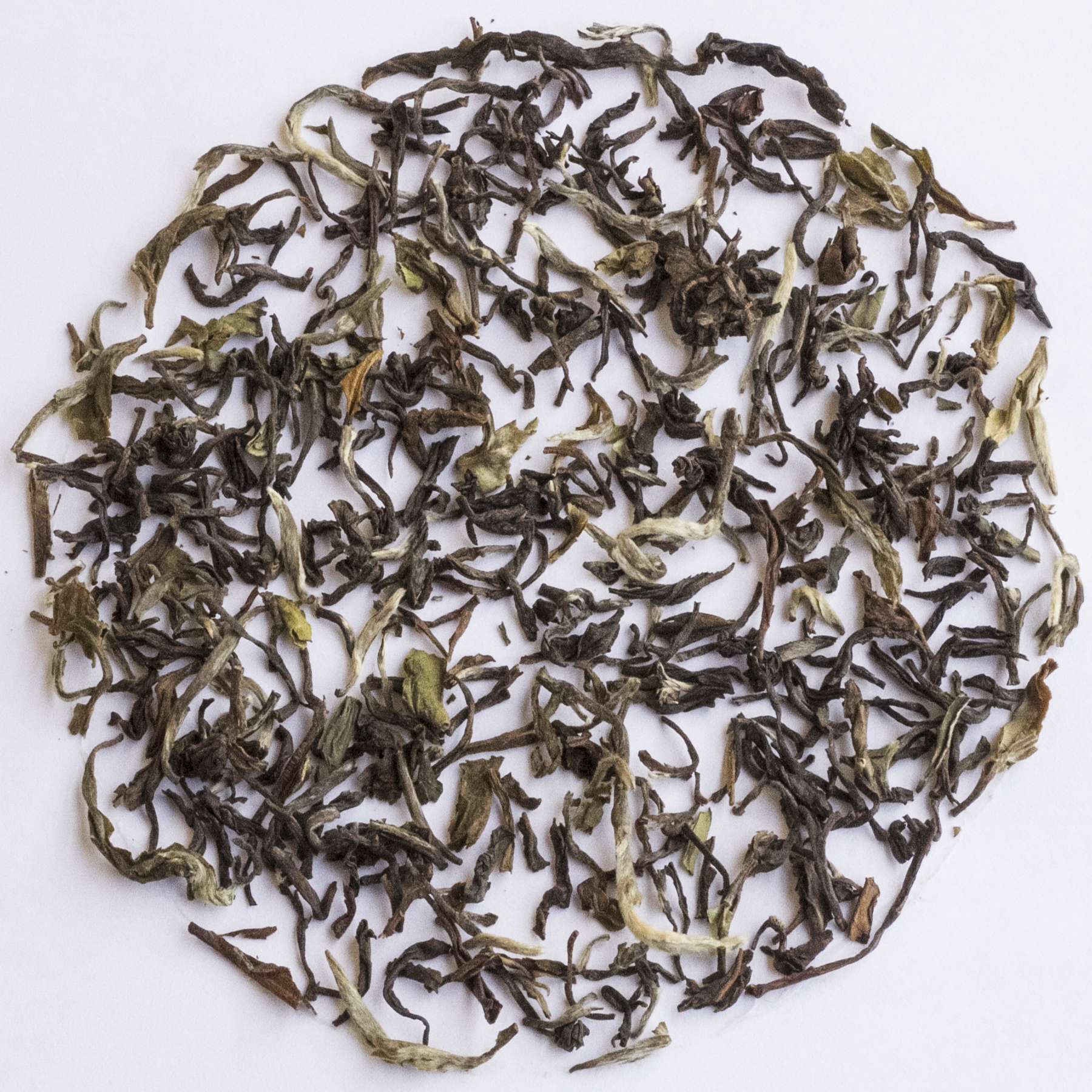Loose-leaf tea leaves arranged in a circular pile on a plain white background.
