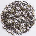 Loose-leaf tea leaves arranged in a circular pile on a plain white background.