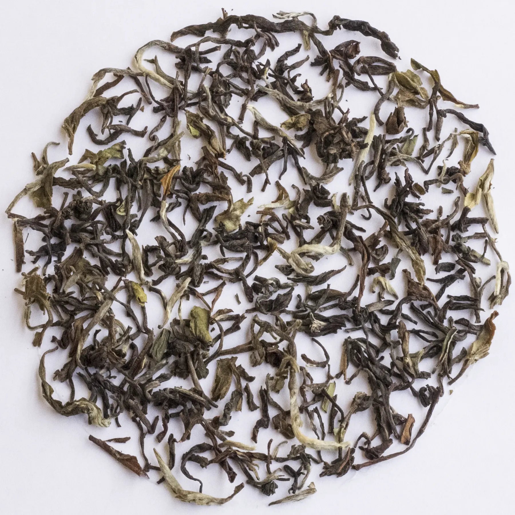 Loose-leaf tea leaves arranged in a circular pile on a plain white background.