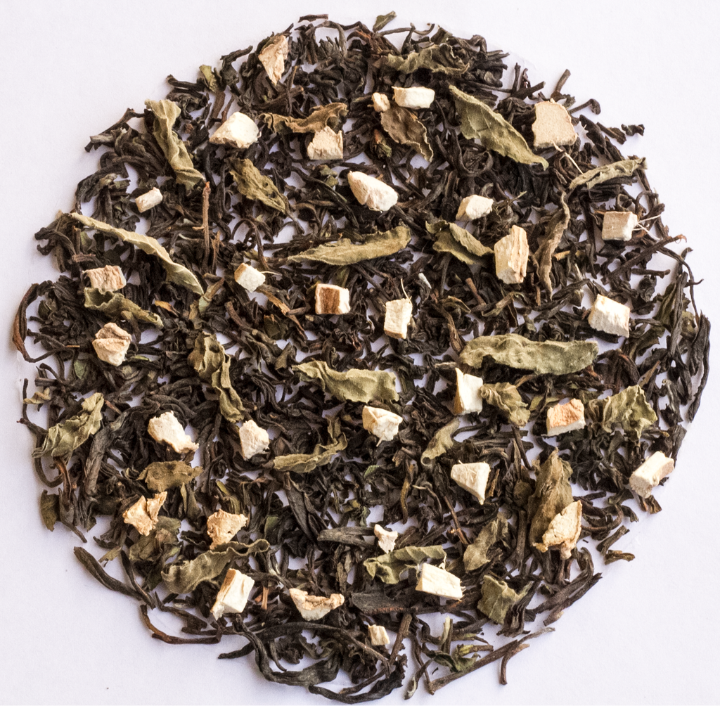 A circular arrangement of loose-leaf herbal tea blend on a plain white background, showing dark tea leaves mixed with pale dried flowers and small light beige chunks.