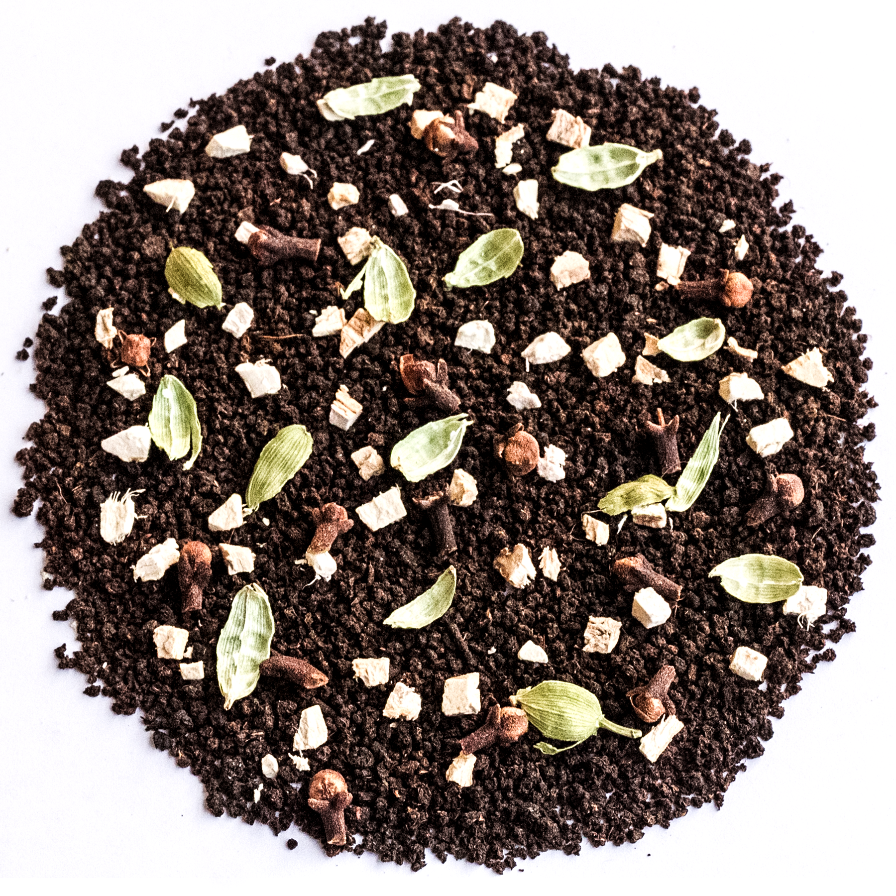 A circular pile of dark chocolate-flavored coffee mix or cocoa powder, featuring whole coffee beans, green cardamom pods, cinnamon sticks, and small white chunks, photographed from directly above on a white background.