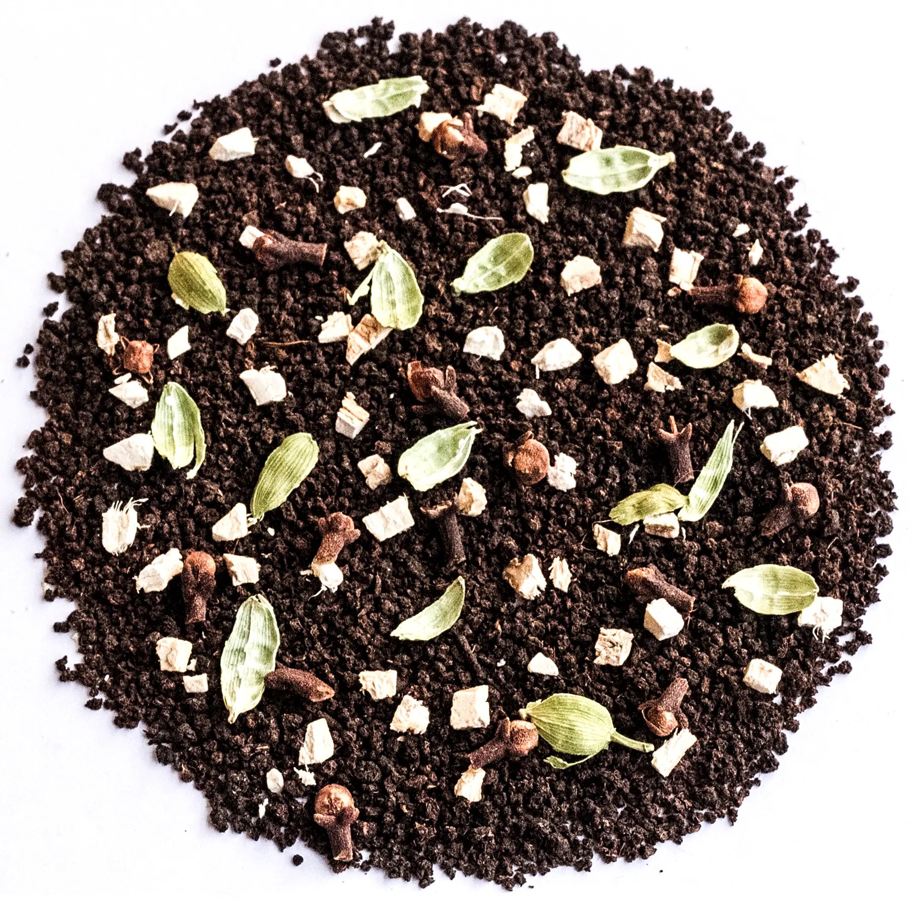 A circular pile of dark brown coffee grounds mixed with whole spices including cardamom pods, cloves, cinnamon sticks, and cubed white sugar, photographed from directly above on a white background.
