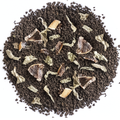 A top-down view of a circular pile of dark brown coffee grounds mixed with dried herbs, leaves, and small brown fruit pieces on a plain white background.
