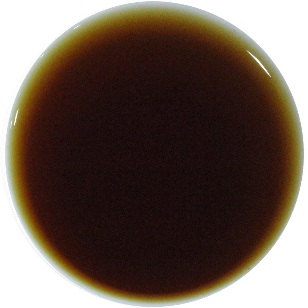 A circular close-up of a dark brown liquid, likely a sauce, syrup, or cosmetic formula, with a glossy finish on a solid white background.