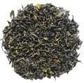 A pile of loose-leaf tea leaves, showing dark green to black rolled leaves with bright yellow-green tips, photographed on a plain white background.