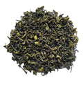 A pile of loose-leaf green tea leaves, showing their curly, dried texture, isolated on a white background.