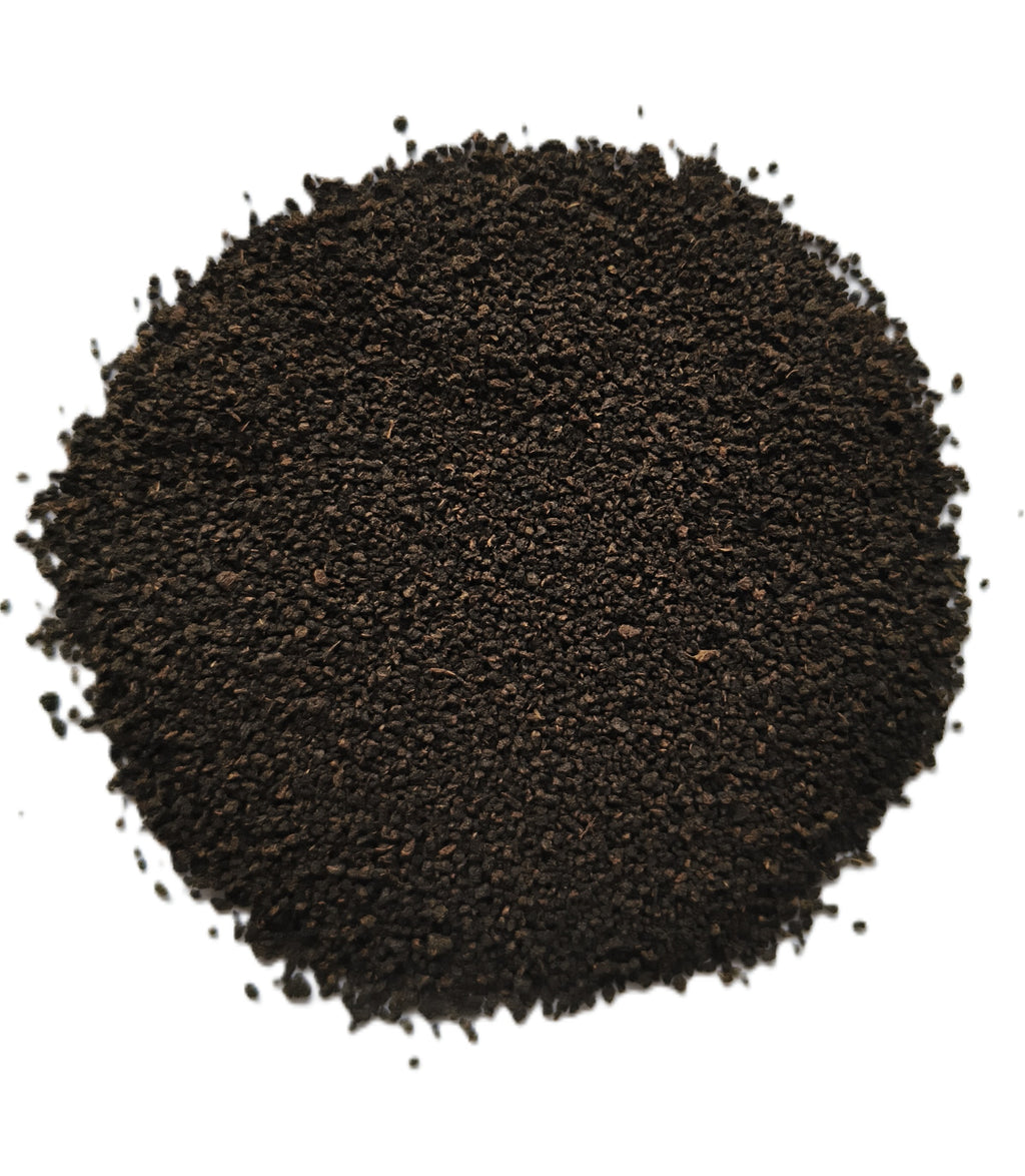 A pile of dark brown to black granular powder or substrate material, photographed from directly above on a plain white background.