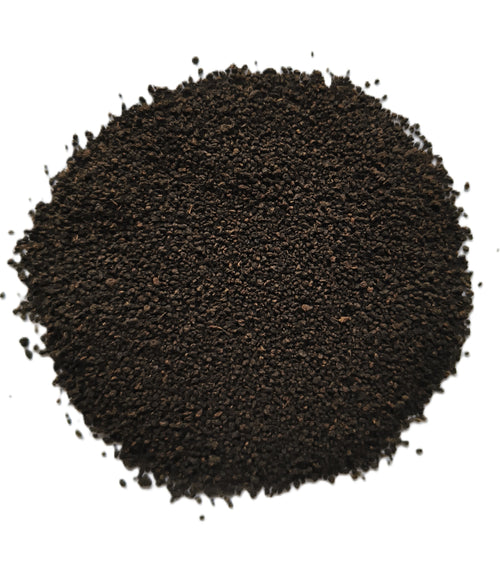 A pile of dark brown to black granular powder or substrate material, photographed from directly above on a plain white background.