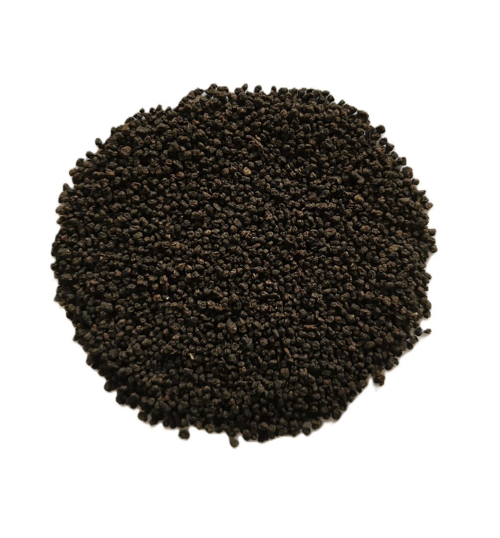 A circular pile of small dark brown to black seeds or grains on a plain white background.