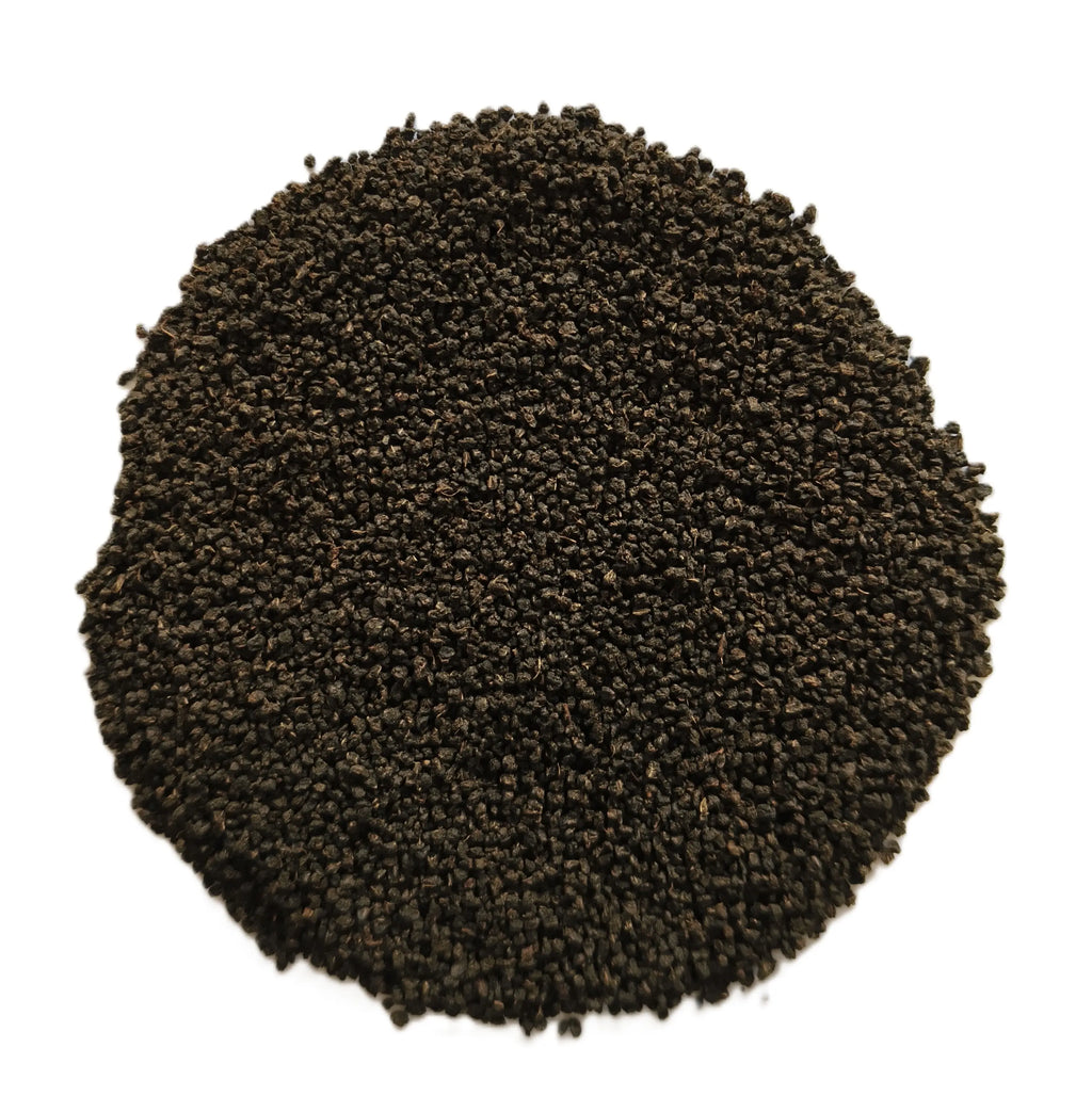 A circular pile of dark brown to black granular material, likely coffee grounds or seed pods, photographed from directly above on a solid white background.