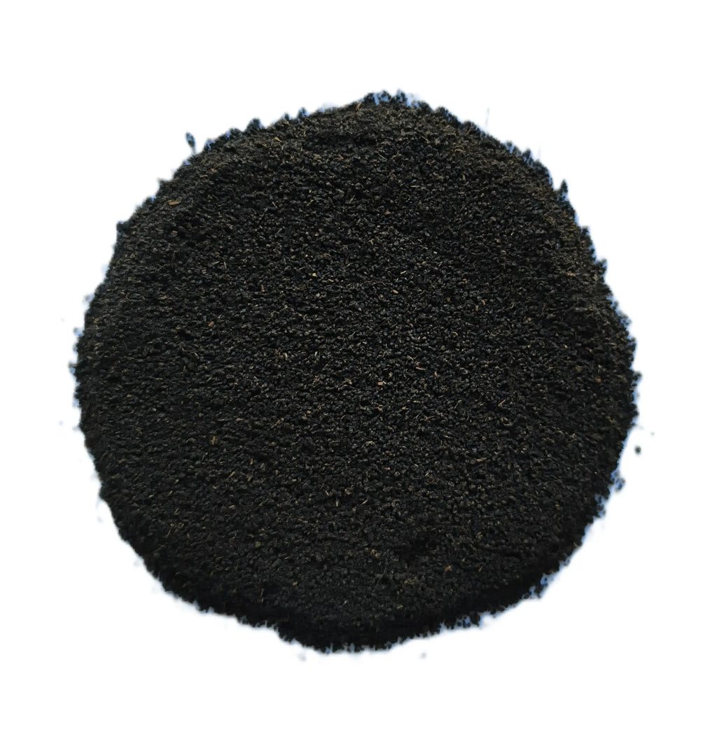 A pile of dark black granular powder or substrate material, photographed from directly above on a solid white background.