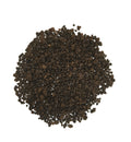 A pile of dark brown textured granules, likely coffee beans or coffee grounds, photographed from directly above on a solid white background.