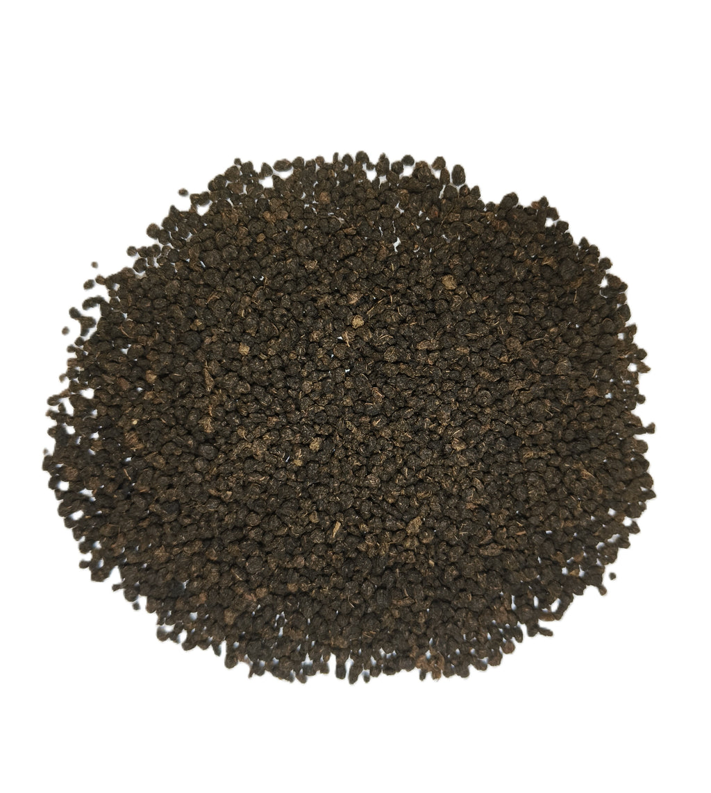 A pile of dark brown to black textured seeds or granules, photographed from directly above on a plain white background.