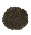 A pile of dark brown to black textured seeds or granules, photographed from directly above on a plain white background.