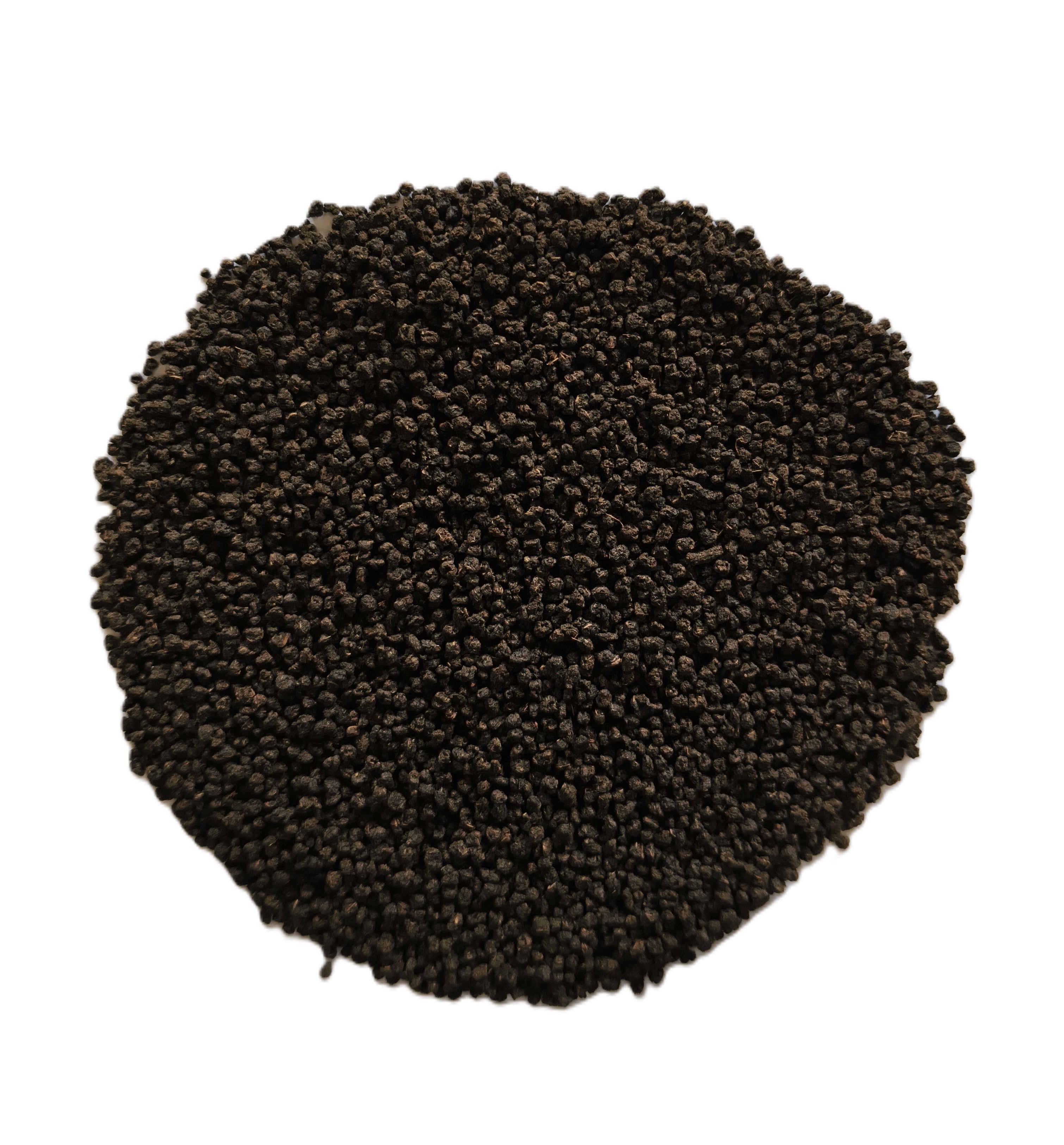 A pile of small dark brown to black granular particles, likely seed, soil, or coffee beans, arranged in a circular mound on a solid white background.