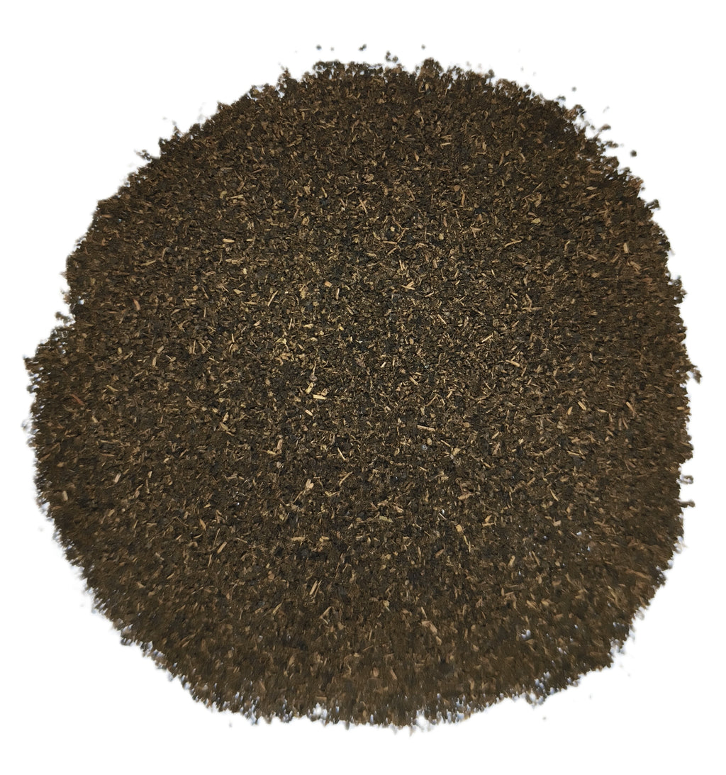 A circular pile of dark brown shredded material, likely coffee grounds or tea leaves, photographed from directly above on a solid white background.