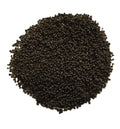 A pile of small dark brown to black seeds, likely sesame seeds, photographed from directly above on a plain white background.