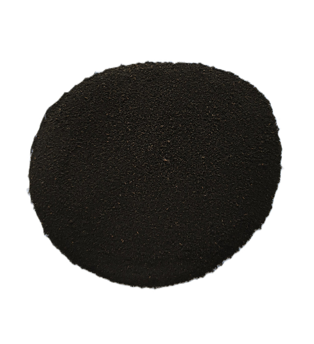 A circular pile of dark black granular powder or substrate material on a solid white background.