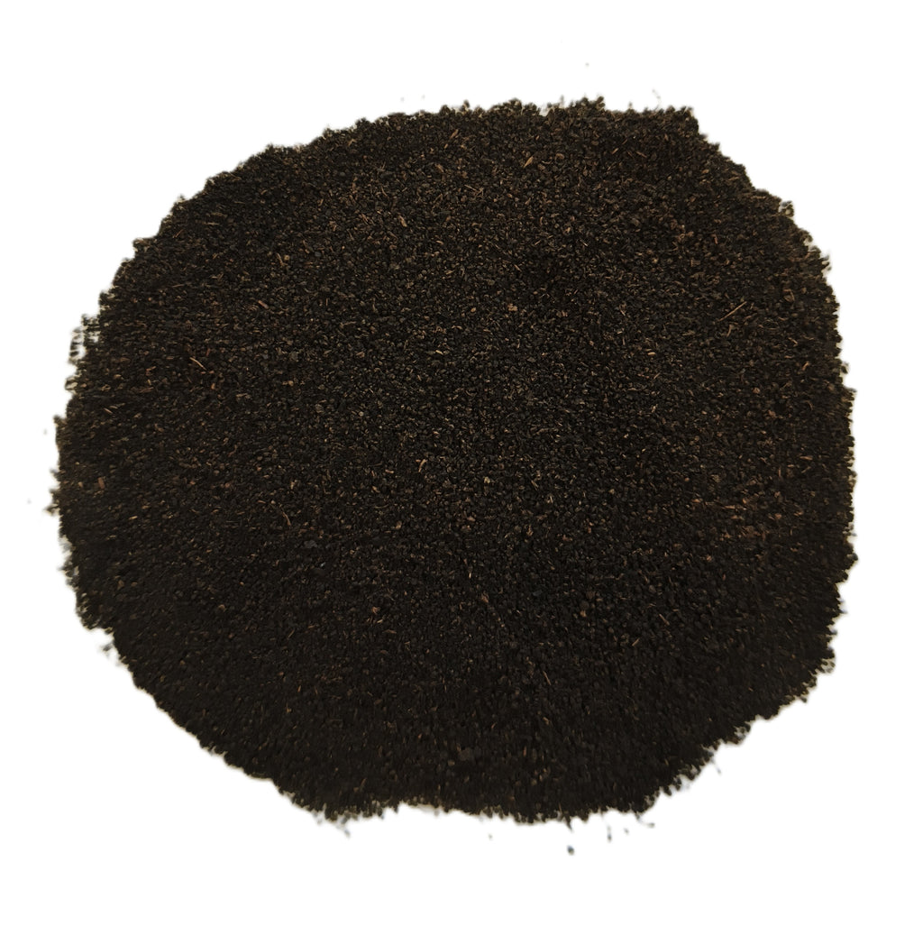 A pile of dark brown to black granular powder or substrate material, photographed from directly above on a plain white background.