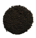 A pile of dark brown to black textured granules, likely coffee beans or a similar ground ingredient, photographed from directly above on a solid white background.