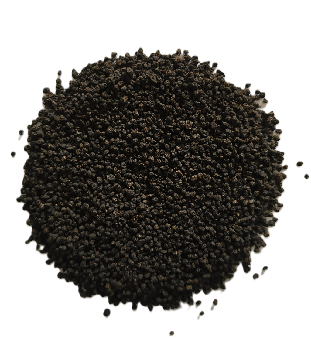 A pile of small dark brown to black seeds or granules photographed from above on a plain white background.