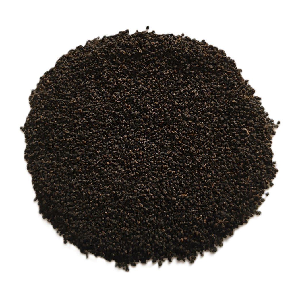 A pile of dark brown to black textured seeds or granules, photographed from directly above on a plain white background.