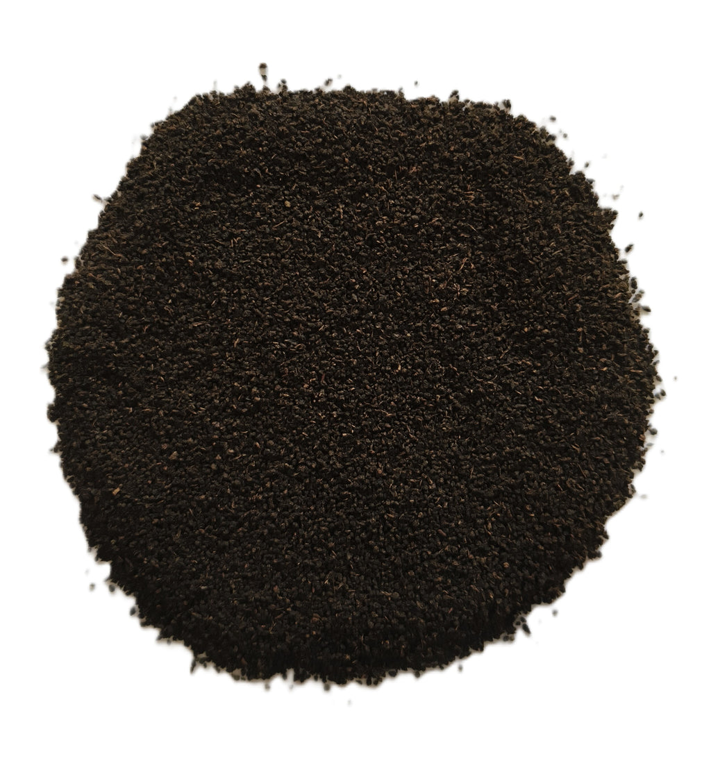 A pile of dark brown to black ground coffee beans or coffee powder, photographed from directly above on a plain white background.
