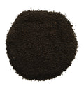 A pile of dark brown to black ground coffee beans or coffee powder, photographed from directly above on a plain white background.