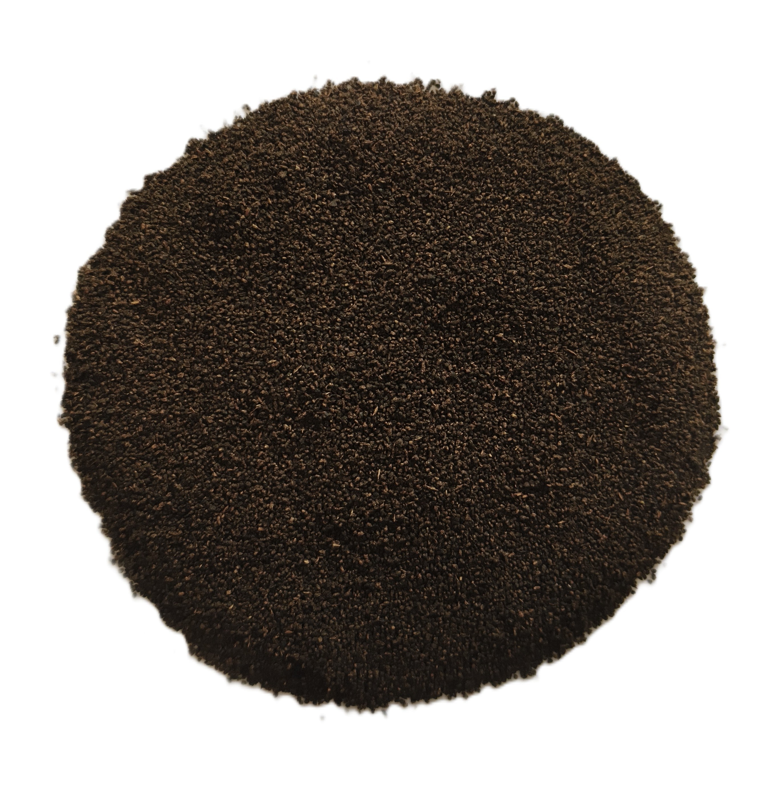 A circular pile of dark brown granular material, likely coffee grounds or seed kernels, photographed from directly above on a solid white background.