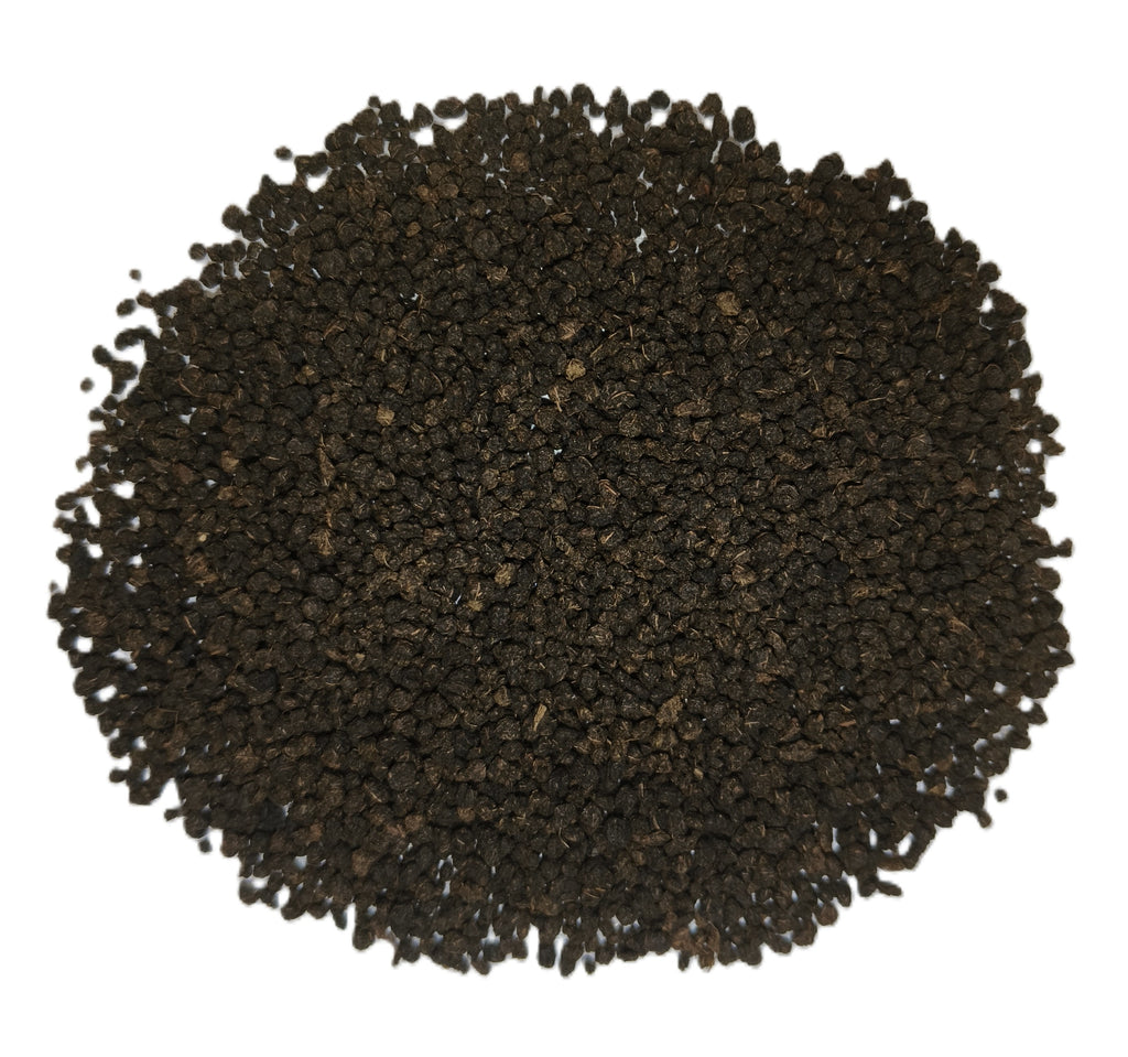 A pile of dark brown to black textured granules, likely coffee beans or tea leaves, photographed from directly above on a solid white background.