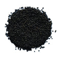 A pile of small, dark brown to black dried seeds or granules, photographed from directly above on a solid white background.