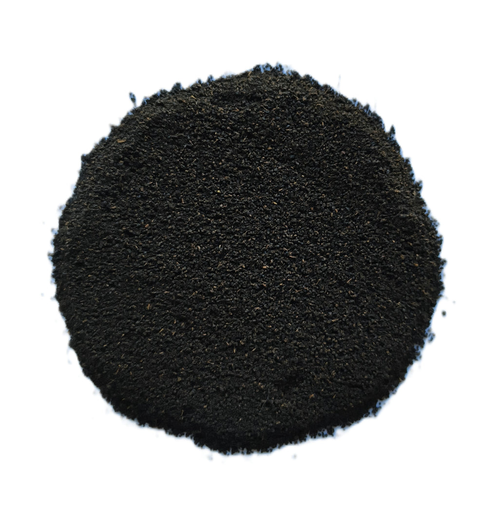 A pile of dark black granular powder or substrate material, photographed from directly above on a solid white background.