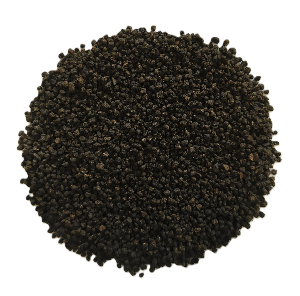 A pile of small dark brown to black seeds or granules photographed from above on a plain white background.