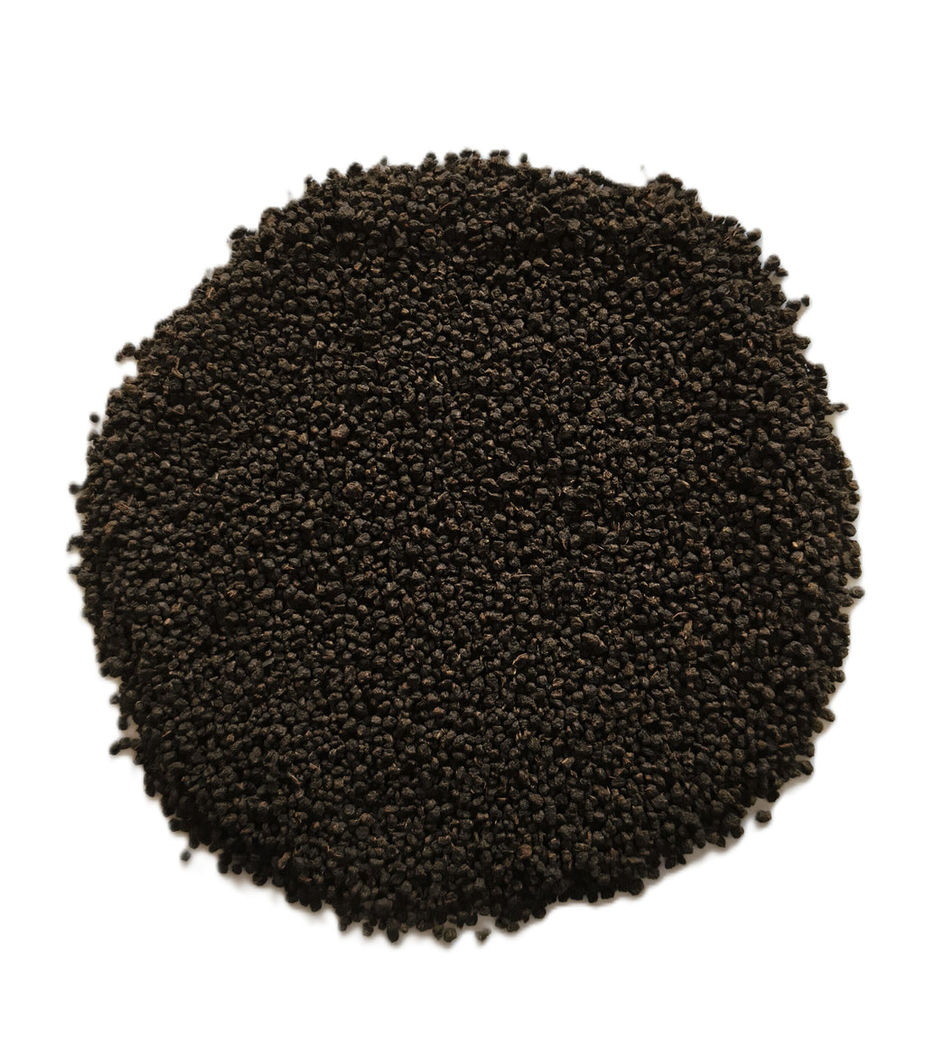 A circular pile of small dark brown to black seeds or granules on a plain white background.