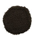 A circular pile of small dark brown to black seeds or granules on a plain white background.