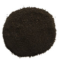A pile of dark brown to black granular powder, likely coffee grounds or a similar fine substance, photographed from directly above on a solid white background.