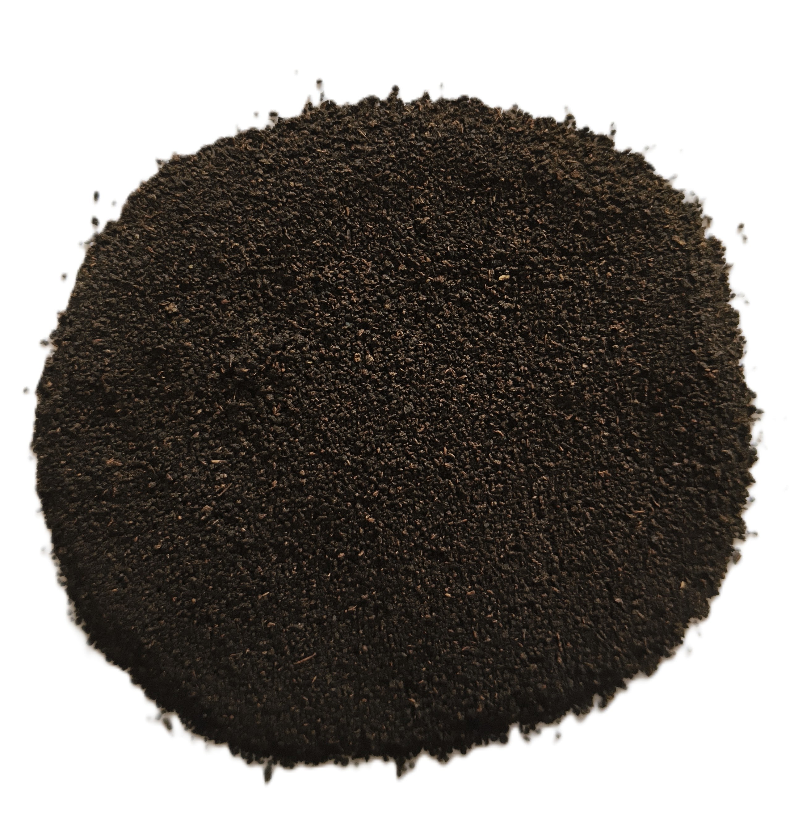 A pile of dark brown to black granular powder, likely coffee grounds or a similar fine substance, photographed from directly above on a solid white background.